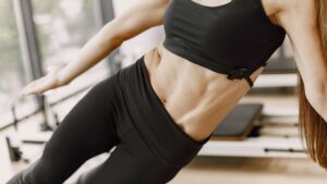 Joga- obserwuj swoje ciało czy robisz postępy. Zdjęcie przedstawia kobietę z napiętymi mięśniami brzucha