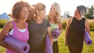 Grupa kobiet w wieku 50+ z matami do jogi - zdjęcie ilustracyjne we wpisie bloga Namaste24.pl "Sport, kobieta, menopauza" 