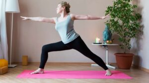 Kobieta ćwicząca na macie do jogi w domu. Zdjęcie ilustracyjne w treści wpisu bloga Namaste24.pl "Sport, kobieta, menopauza"