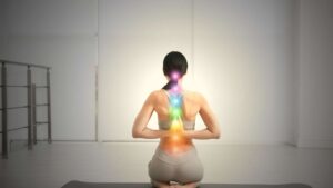 Kobieta na macie do jogi odwrócona plecami i z zazanczonymi czakrami
